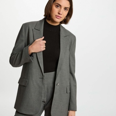 Mulher com blazer cinzento e camisola preta, fundo branco
