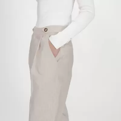 Calças bege claro com bolso e cinto, usada com camisola branca canelada