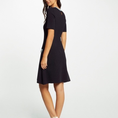 Vestido preto curto com manga curta usado por mulher em fundo branco