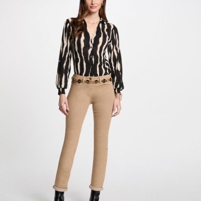 Mulher a usar blusa preta e branca e calças cinza claras com botas pretas