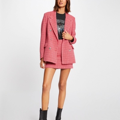 mulher a usar casaco rosa, saia rosa, t-shirt preta e botas pretas