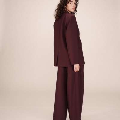 Conjunto de fato feminino castanho com blazer e calças largas em fundo neutro