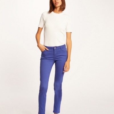 Mulher com camisola branca de manga curta e calças azul vivo em fundo branco