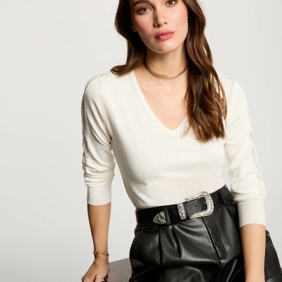 Mulher com camisola branca e calções pretos sentada numa cadeira de madeira