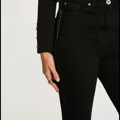 Calças justas pretas em tecido denim com camisola preta de manga longa e botões dourados.