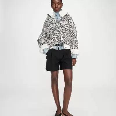 Mulher com blusão padrão zebra branco e preto, camisa jeans e calções pretos