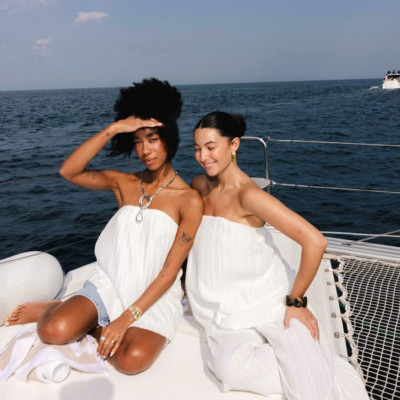 Duas mulheres em iate vestindo tops brancos plissados