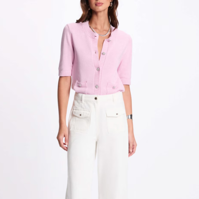 Mulher a usar camisola rosa de malha com botões e calças brancas com bolsos