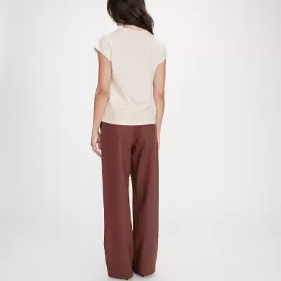 Mulher com t-shirt bege e calças castanhas vistas de costas em fundo branco