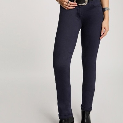 Calças justas azul escuro com cinto preto e botas pretas em fundo neutro