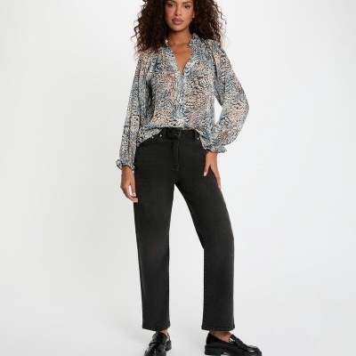 Mulher com blusa estampada azul e bege, calças pretas e sapatos pretos em fundo branco