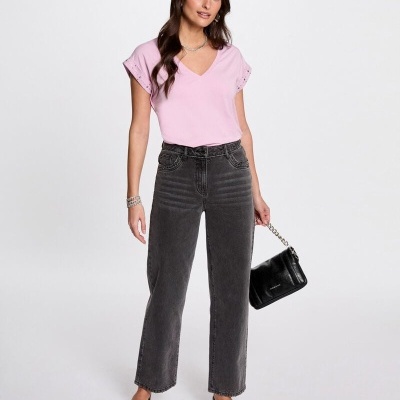 Mulher com t-shirt rosa, calças de ganga cinzentas e mala preta em fundo branco