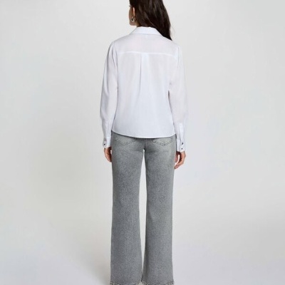 Mulher de costas com camisa branca de manga comprida e calças de ganga cinza