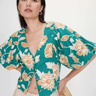 Blusa floral verde com botões e mangas bufantes usada por mulher.