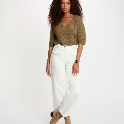 Mulher com blusa castanha, calças brancas largas e botins camel