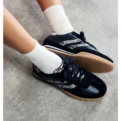 Ténis pretos com padrão pele de cobra e sola castanha.