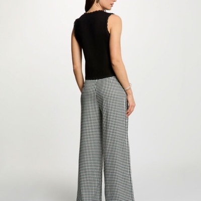 Mulher vestindo top preto sem mangas e calças xadrez em fundo branco