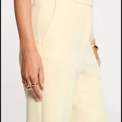 Calças creme com bolso lateral e cintura alta usadas por pessoa com anéis dourados