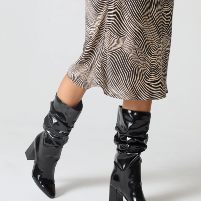 Botas pretas de salto alto em verniz com saia midi padrão ondulado