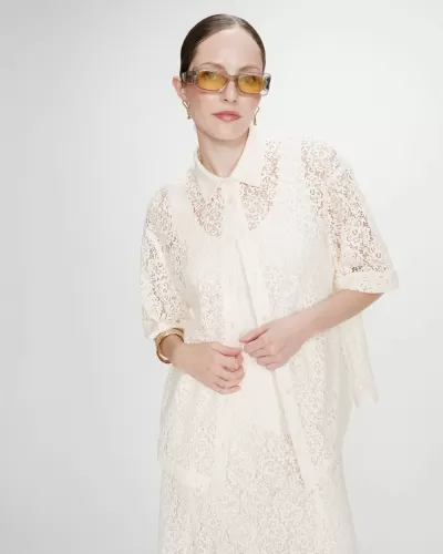 Camisa e saia rendadas creme com padrão floral, óculos de sol com lentes amarelas e armação transparente.