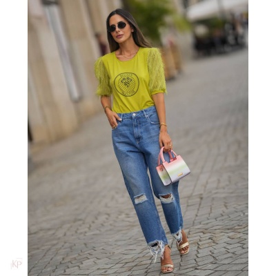 Mulher com t-shirt amarelo-limão de mangas de tule, jeans azuis rasgados, mala rosa e branca, sandálias brancas e óculos de sol num passeio urbano.