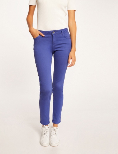 Calças azuis justas femininas com t-shirt branca e ténis brancos num fundo claro