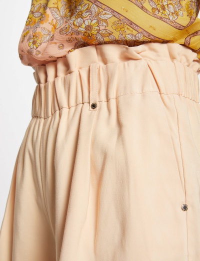 Calças bege com cintura elástica e blusa amarela floral