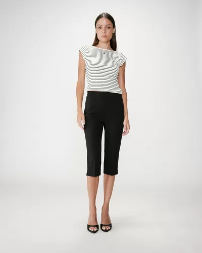 Mulher com blusa branca com riscas pretas e calças pretas até meio da perna