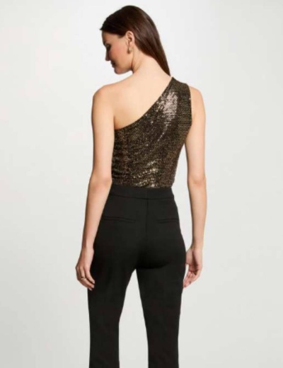 Mulher vista de costas a usar top de um ombro com lantejoulas e calças pretas.