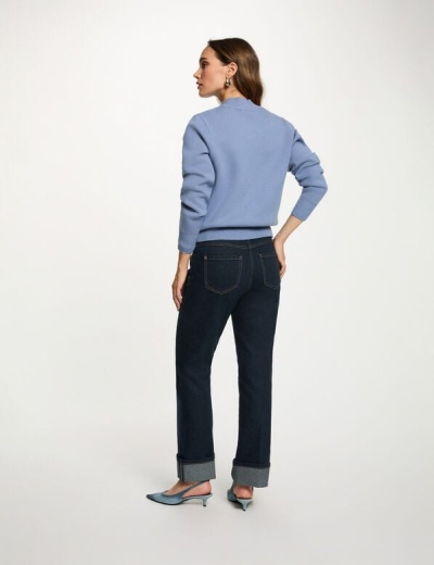 Mulher de costas com camisola azul, calças de ganga e sapatos de salto