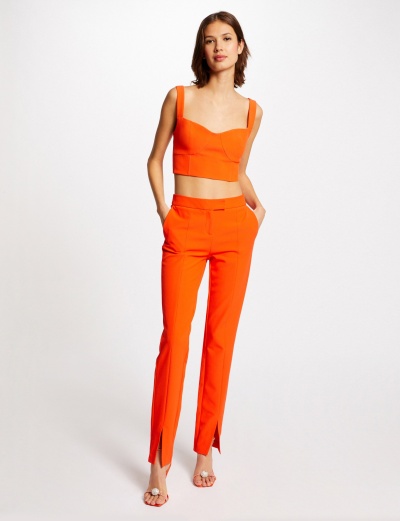 Mulher a usar conjunto laranja com top cropped e calças com fendas na bainha