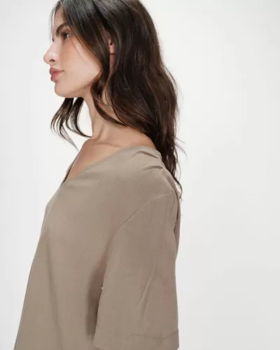 Mulher de perfil com túnica bege de manga curta