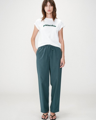 Modelo com t-shirt branca pistacchio e calças azuis largas