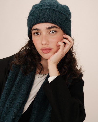 Mulher a usar gorro e cachecol azuis de malha com textura felpuda e casaco preto