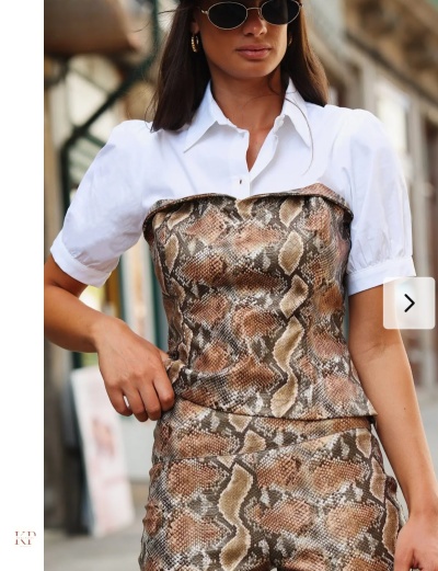 Mulher usando camisa branca com colete e saia de padrão pele de cobra outdoors.