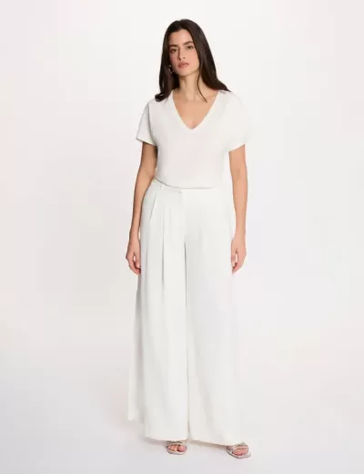 Mulher a usar conjunto branco com blusa de manga curta e calças largas.