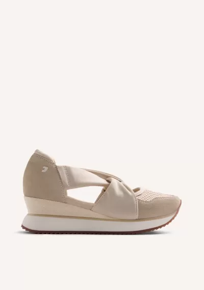 Tênis bege com cunha e design recortado sobre fundo claro