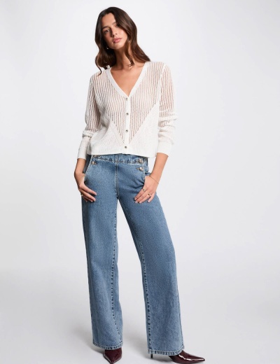 Mulher com camisola branca de malha e calças de ganga azuis