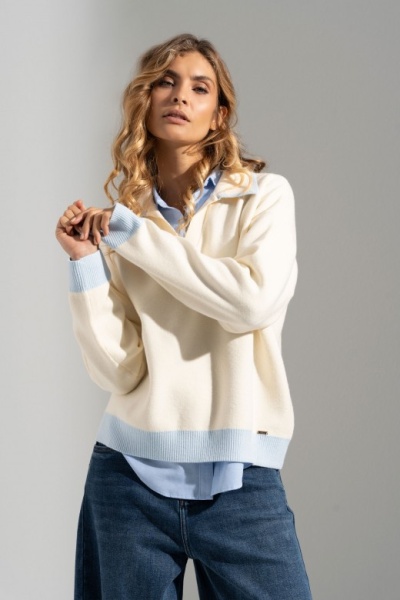Mulher veste suéter creme com detalhes azul claro e calças de ganga azul escuro