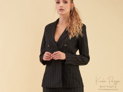 Blazer feminino preto riscas brancas usado por mulher, fundo bege claro.