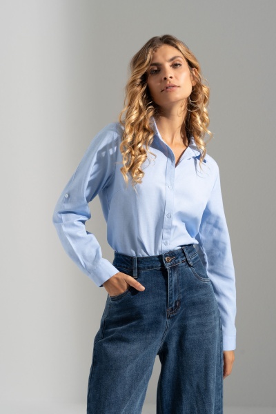 Mulher com camisa azul clara de manga comprida e calças de ganga azul escuro