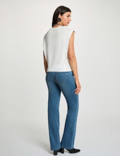 Mulher de costas com camisola branca sem mangas e calças de ganga azuis