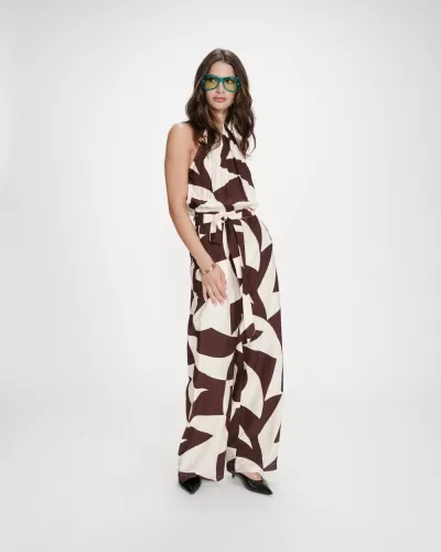 Macacão branco e castanho com padrão abstrato usado por mulher com óculos verdes.