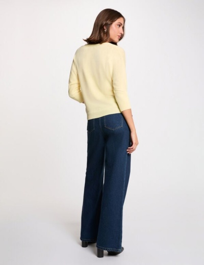 Mulher de costas com camisola amarela e calças de ganga azul escuras