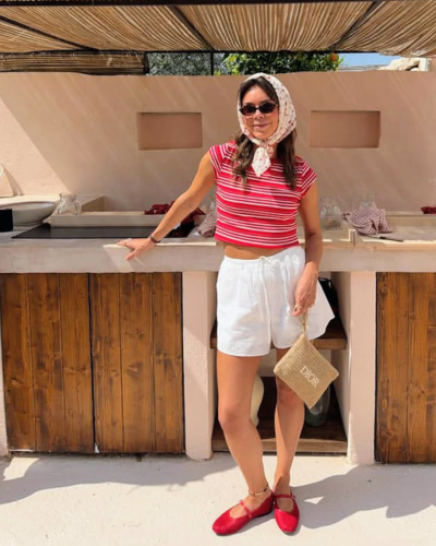 Pessoa com roupa casual vermelha e branca com bolsa Dior à frente de balcão de madeira em área exterior