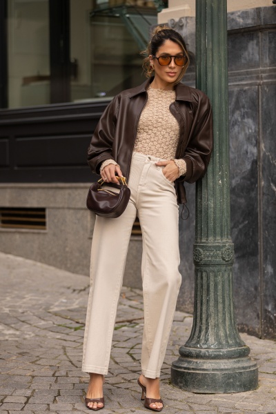 Mulher com roupas de outono casuais e acessórios castanhos, encostada a um poste de rua