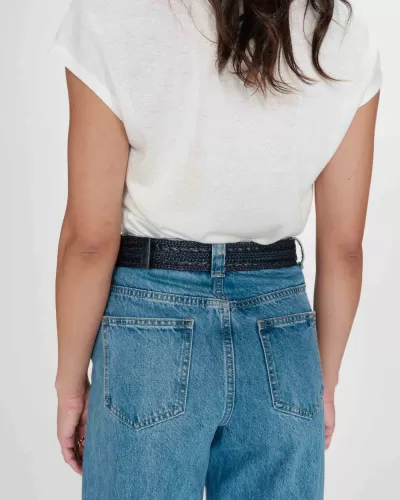 Pessoa com t-shirt branca e calças de ganga azul com cinto preto, vista de trás