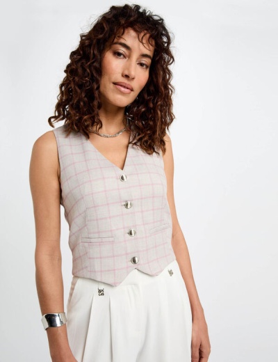 Colete xadrez rosa e branco com botões prateados, calças brancas e pulseira metálica