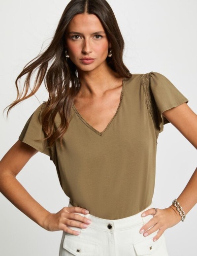 T-shirt verde-oliva de manga curta com detalhes em renda usada por mulher com calças brancas
