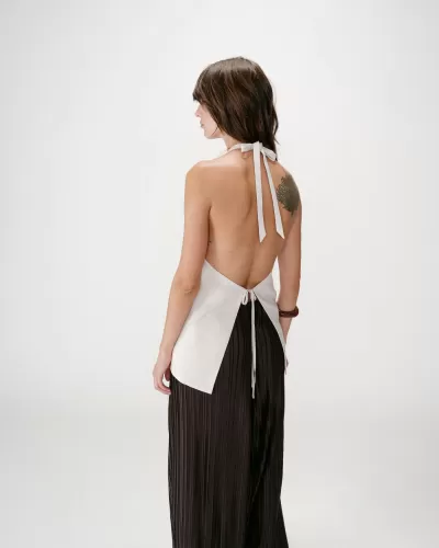 Mulher de costas com top branco sem costas e calças pretas plissadas